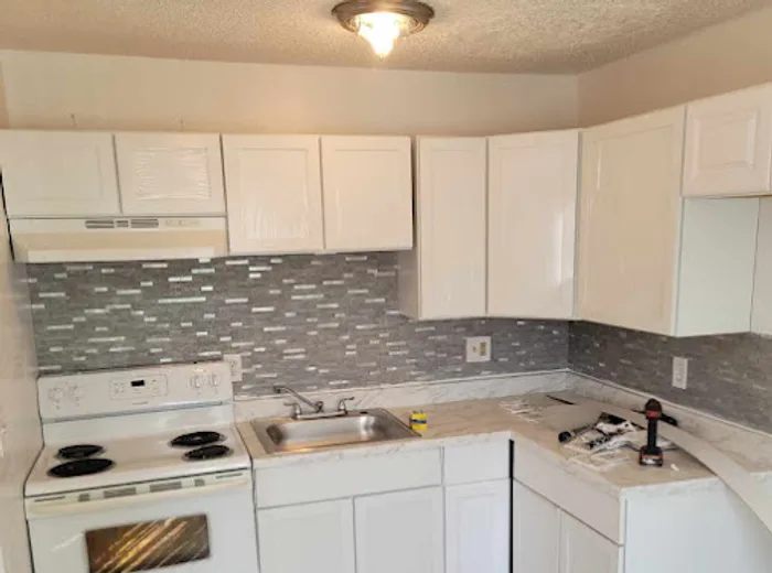 Remodeled kitchen with white cabinets and mosaic backsplash in DFW
